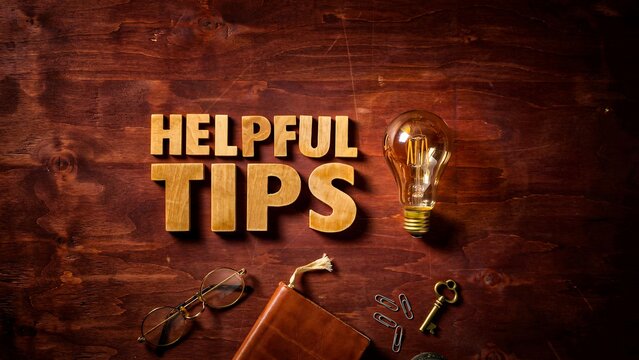 Helpful tips text with glowing light bulb on wooden desk for business advice concept