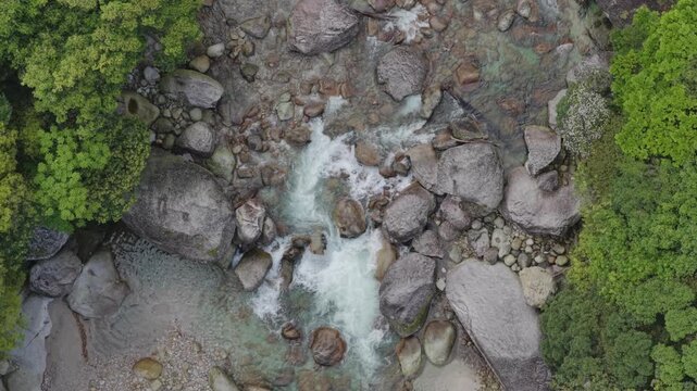 Top down view of rocky river and cascades through forest on Yakushima Island, Japan
