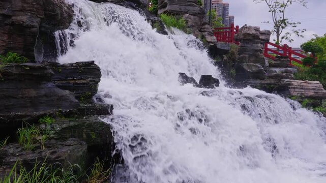 Panoramic picture of multi-layered waterfalls flowing among green rockeries
