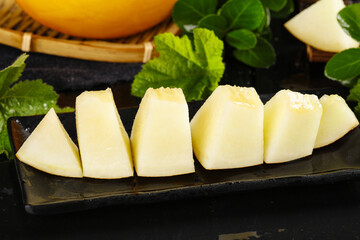 Fresh Honeydew Melon Slices with Mint Leaves on Slate Board - Sweet Golden Fruit Display © DinhThi