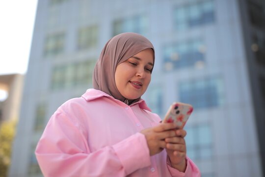 Woman in hijab using her smartphone outdoors
