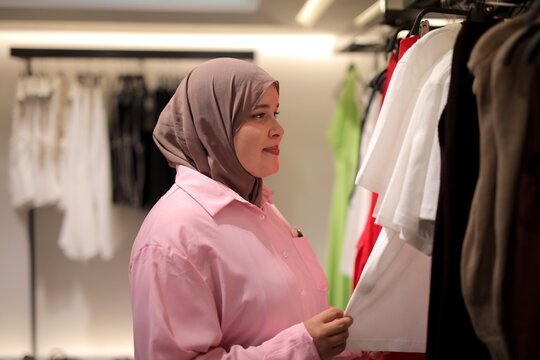 Young woman in a hijab browsing clothes in a store