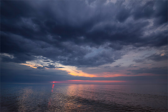 Dark storm clouds over calm ocean during sunset