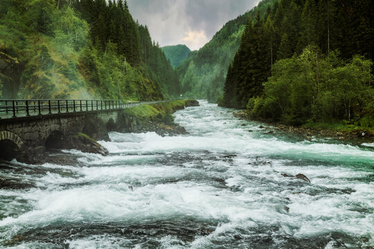 Rushing mountain river flowing by a stone bridge