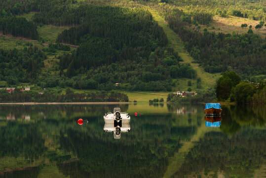 Small motorboats anchored in calm lake with reflection
