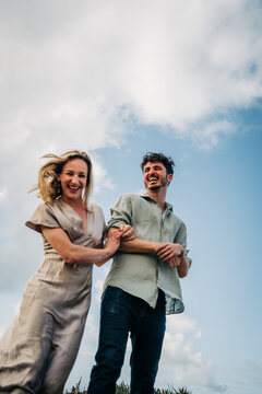Young couple laughing together against a blue sky