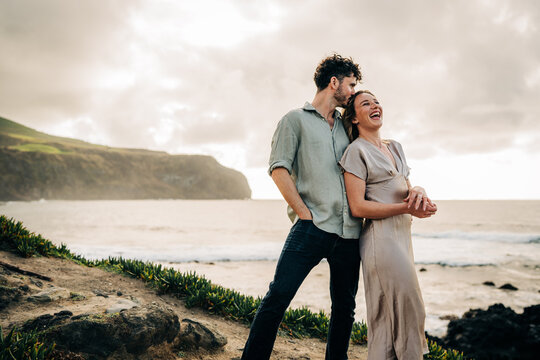 Joyful couple laughing together on a seaside cliff