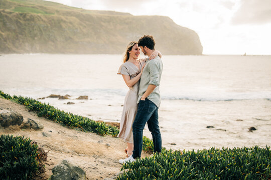 Affectionate couple laughing together on a coastal cliff
