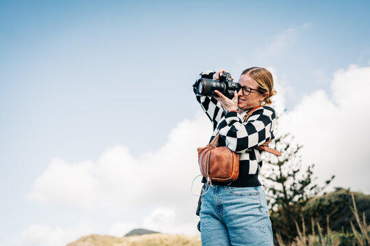 Young woman photographer taking photos outdoors