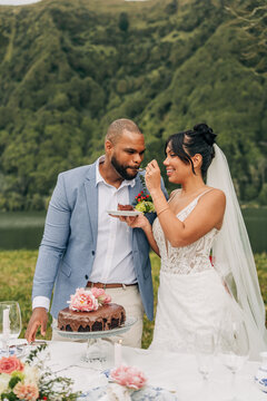 Happy bride feeds groom a bite of wedding cake