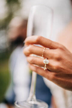 Woman showing her diamond engagement ring holding champagne