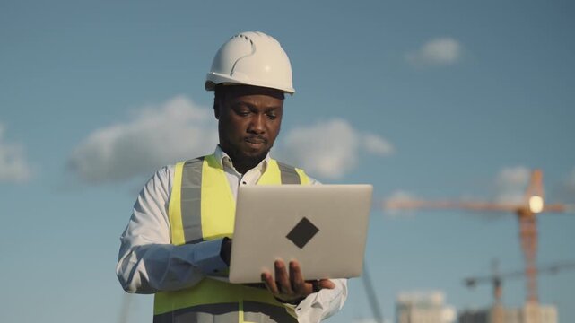 Audit and expertise in construction site, portrait of african american engineer. Professional builder working with laptop, making report about building works, architect control project implementation