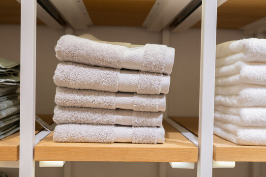 Beige towels stacked and folded on wooden retail shelf