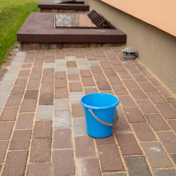 Blue bucket on brick patio of residential building