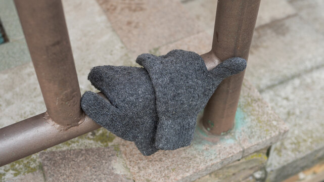 Gray wool glove on metal railing outdoors