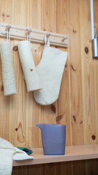 Wooden sauna interior with loofahs and blue water jug on wooden shelf
