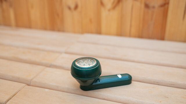 Green fabric shaver on wooden surface in minimalist setting