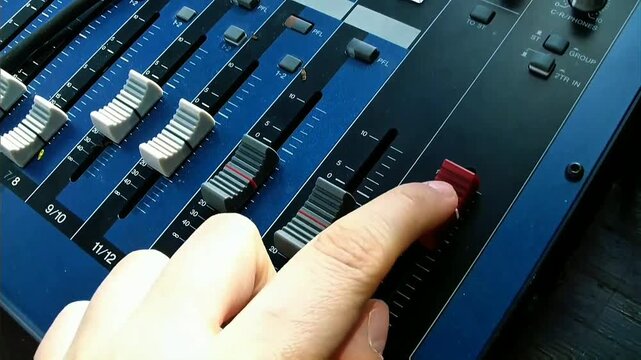 Professional audio mixing console with clearly marked white, gray, red sliding faders on deep blue control surface