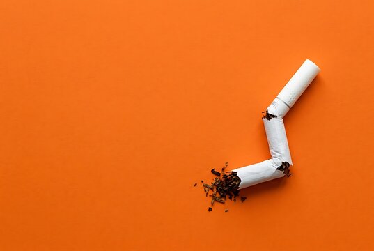 Broken cigarette on orange background, symbolizing smoking cessation and healthy lifestyle.