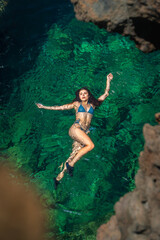 Fototapeta premium Woman floating in clear green ocean water