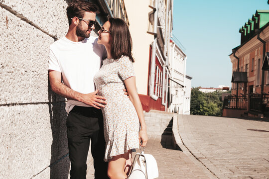 Smiling beautiful woman and her handsome boyfriend. Woman in casual summer clothes. Happy cheerful family. Female having fun. Couple posing on the street background in sunglasses.Hugging each other
