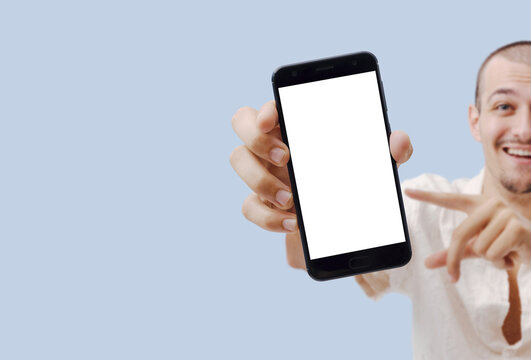 Man Showing Empty Smartphone Screen, Pointing with Finger, Blue Background