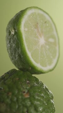 A slice of bergamot in close up shot, standing above another one with dripping glycerin on a green background.