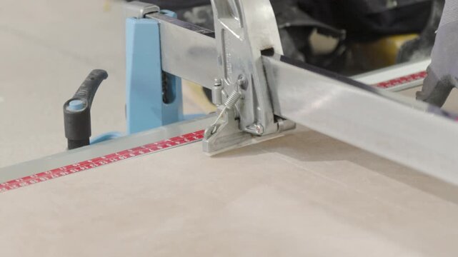 Tiler cutting a big tile with a professional cutter. Construction worker.
