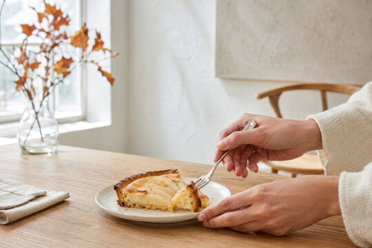 Disfrutar de una rebanada de tarta de pera con almendra en una mesa de madera