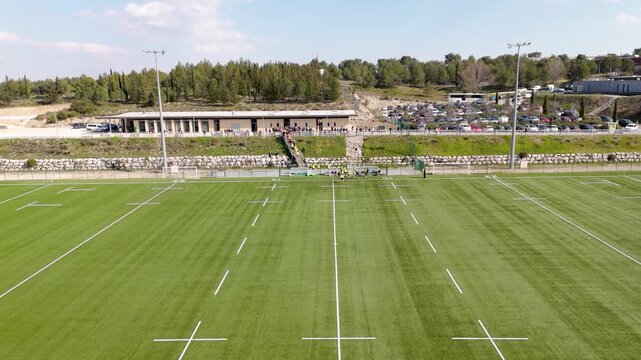 Rugby players entering the field for a match. Team running onto the grass pitch in a stadium, preparing for the gam with spectators in the background.