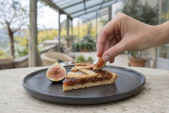 Un postre de crostata con higo en un caf&eacute; al aire libre, rodeado de plantas, en un d&iacute;a soleado