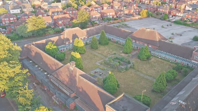 Doncaster School for the Deaf on Leger Way, Doncaster, South Yorkshire, England, features a quadrangular brick campus enclosing a landscaped courtyard with mature trees, drone ascent establishing shot