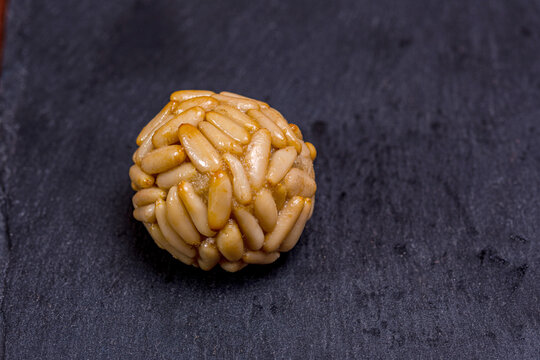 Panellets covered with pine nuts resting on dark slate plate