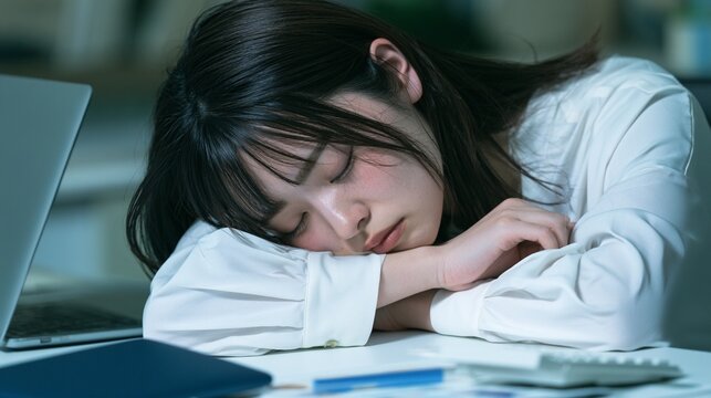 デスクでうたた寝をする疲れた日本人女性会社員