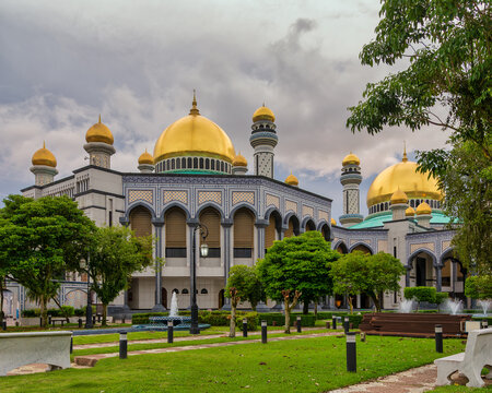 Majestic Jame' Asr Hassanil Bolkiah Mosque, Bandar Seri Begawan, Brunei Golden domes, intricate architecture, lush gardens, and fountains under a cloudy sky
