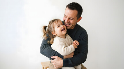 Fototapeta premium Father holding laughing baby in studio portrait. Happy dad bonding with infant child in neutral minimalist setting.