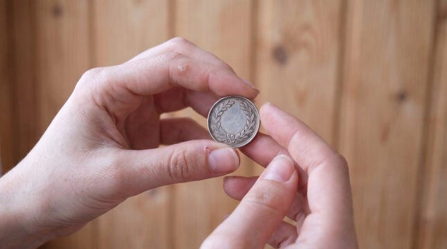 Hands holding a coin in front of wooden background  