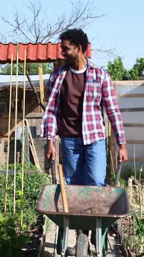 Young black farmer pushing a wheelbarrow in a community garden