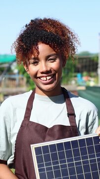 Smiling african american farmer holding solar panel in garden