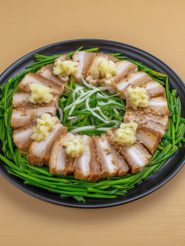 Delicious pork belly chashu with ginger and garlic on a black plate