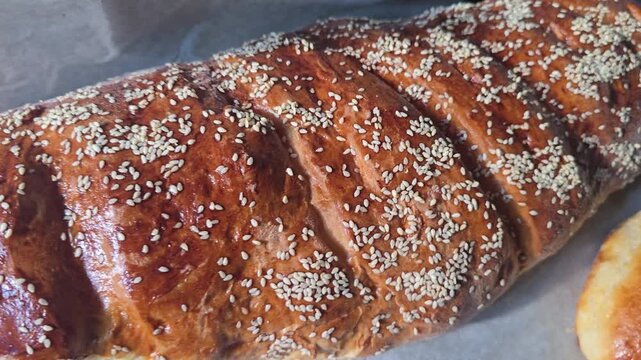 Fresh homemade loaf of bread with sesame seeds and a golden crispy crust shining in sunlight. Close-up of artisan bakery product, perfect for food, baking, nutrition, homemade and healthy eating conce