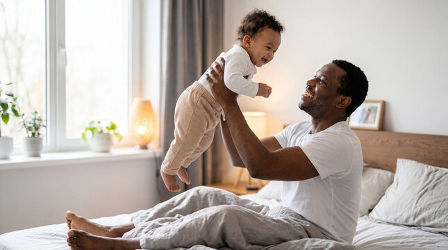 Father holds baby above his head with joy in a bright bedroom during the day