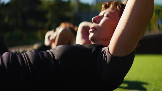Elderly women practicing gentle Pilates core exercises in slow motion on outdoor mats, focusing on mindful movement, flexibility, and healthy senior fitness together
