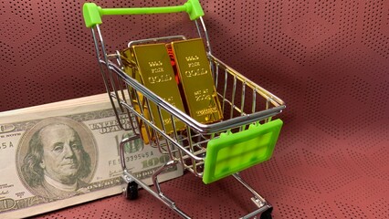 Gold bars and a hundred-dollar bill displayed in a miniature cart representing diversified financial investments © MR HEPPY