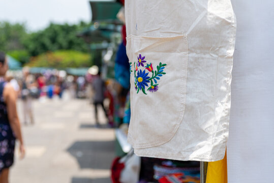 Traditional Mexican Embroidered Cotton Apron Displayed at Outdoor Artisan Market
