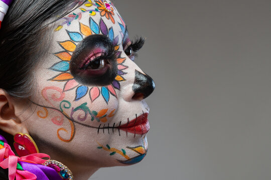 Close Up Portrait of Woman with Colorful Catrina Makeup for Day of the Dead on Gray Background