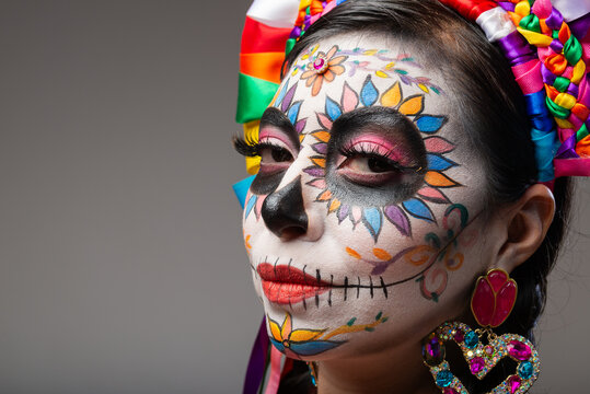 Close Up Portrait of Woman with Colorful Catrina Makeup for Day of the Dead on Gray Background