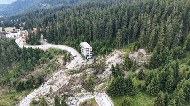 Aerial reveal shot of mountain landslide damage near road and building