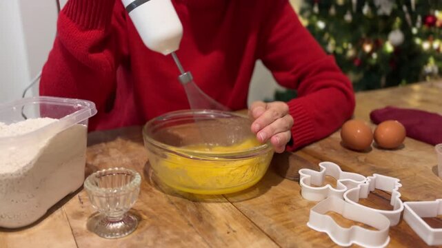 Mujer batiendo masa de galletas con batidora en Navidad
