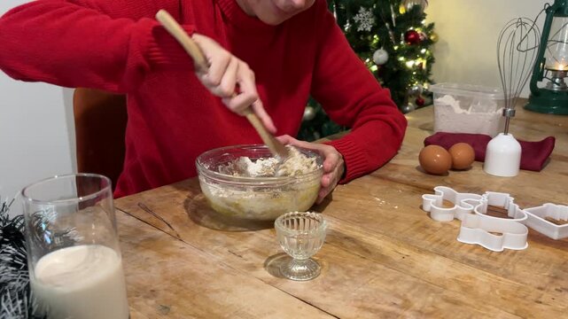 Mujer mezclando masa de galletas con cuchara en Navidad